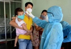 A health worker checks the temperature of residents at the area of a newly found coronavirus infected patient in Da Nang city, Vietnam, July 26, 2020.