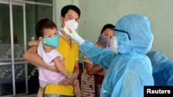A health worker checks the temperature of residents at the area of a newly found coronavirus infected patient in Da Nang city, Vietnam, July 26, 2020.