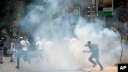 FILE - University students run as police use tear gas to disperse them during a demonstration in Nairobi, Kenya, Sept, 22, 2015.