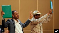 Gen. Mohamed Hamdan Daglo, the deputy head of the military council, right, and protest leader Ahmed Rabie hold up a signed agreement at a ceremony attended by African Union and Ethiopian mediators in the capital Khartoum, Sudan, August 4, 2019.