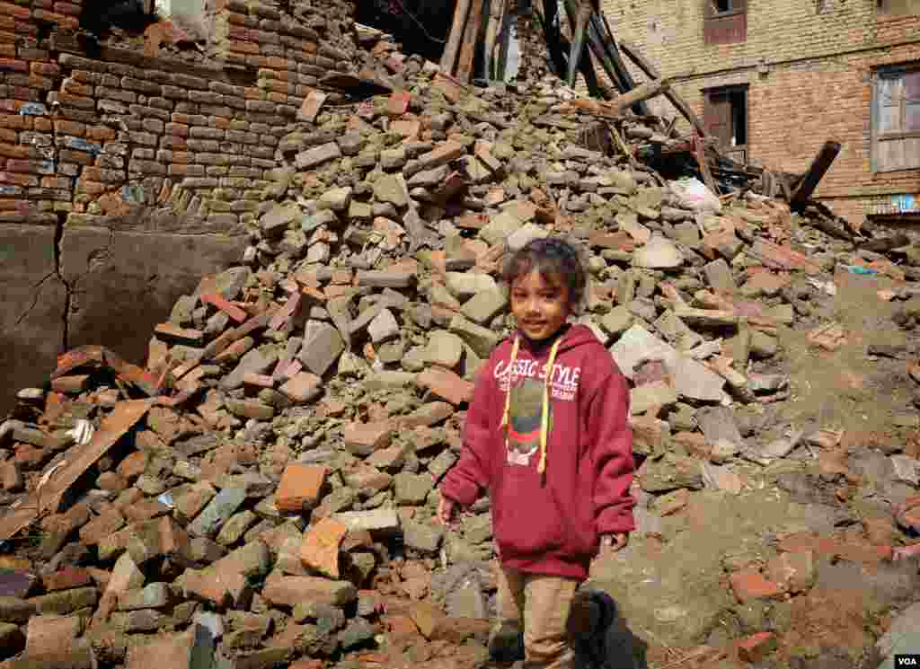 A girl returns to her destroyed home to search for belongings. She later found one of her toys, Sankhu, Nepal, April 29, 2015. (Rosyla Kalden/VOA)