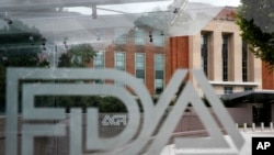 FILE - The U.S. Food and Drug Administration building is seen behind FDA logos at a bus stop on the agency's campus in Silver Spring, Maryland, Aug. 2, 2018.