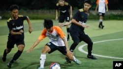 In this July 15, 2018, photo, Wild Boars soccer team, in black, play a local team during a Mae Sai league match in Mae Sai district in Chiang Rai province, northern Thailand. 