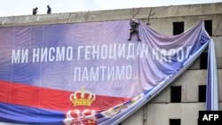 Radnici postavljaju baner sa natpisom "Mi nismo genocidan narod. Pamtimo" u Beogradu (foto: OLIVER BUNIC / AFP)