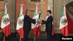 Tổng thống mãn nhiệm Mexico Felipe Calderon (trái) trao quốc kỳ cho tân Tổng thống Enrique Pena Nieto tại buổi lễ giữa khuya ở Dinh Tổng thống ở Mexico City, 1/12/2012