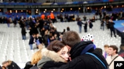 Fans comfort each other after descending onto the playing field in Stade de France stadium at the end of the friendly soccer match between France and Germany in Saint Denis, outside Paris, Nov. 13, 2015, the night of the terror attacks.
