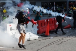 FILE - A protester throws back a tear gas canister during demonstrations in Hong Kong, Aug. 5, 2019.