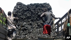 FILE - Somali porters offload charcoal from a truck at a charcoal market in Mogadishu, Oct. 30, 2012.