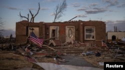 A US flag is tied to a fallen tree in front of a destroyed residence in the aftermath of a tornado in Mayfield, Ky.,Dec. 14, 2021.