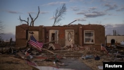 Sebuah bendera AS diikat ke pohon tumbang di depan tempat tinggal yang hancur setelah bencana tornado. (Foto: Reuters)