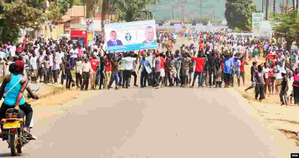 Angry voters in Kampala who say they were denied their ballots march on the police line with a Kizza Besigye poster.