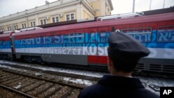 A railroad worker stands by a train covered with slogans reading "Kosovo is Serbia," written in several languages, departing Belgrade for Mitrovica, Kosovo, Jan. 14, 2017.