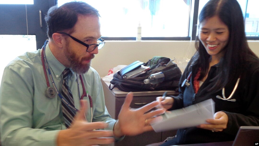 In this Wednesday, Sept. 23, 2015 photo, Dr. Rick Sacra reviews patient cases with Dr. Anna Chon at the Family Health Center in downtown Worcester, Mass., where he advises doctors in training. 