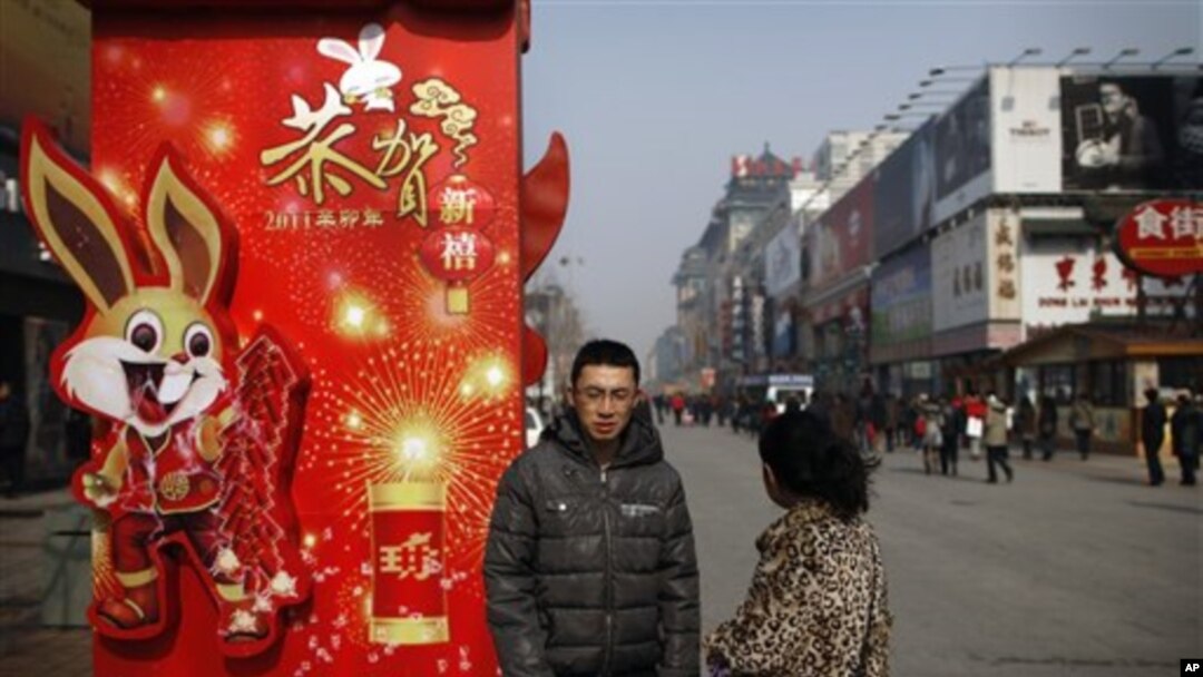 A Chinese couple takes a rest next to a new year decoration on displayed along a shopping district in Beijing, Feb 15, 2011