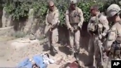 This image made on Thursday, Jan. 12, 2012 from undated video posted on the Internet on Wednesday, Jan. 11, 2012 by a YouTube user who identified self as "semperfiLoneVoice" shows men in U.S. Marine combat gear, standing in a semi-circle over three bodies