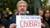 Russian politician Grigory Yavlinsky holds a poster reading: "Freedom to Konstantin Kotov", an opposition activist in jail, during a protest in the center of Moscow, Russia, Aug. 17, 2019.