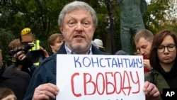 Russian politician Grigory Yavlinsky holds a poster reading: "Freedom to Konstantin Kotov", an opposition activist in jail, during a protest in the center of Moscow, Russia, Aug. 17, 2019.