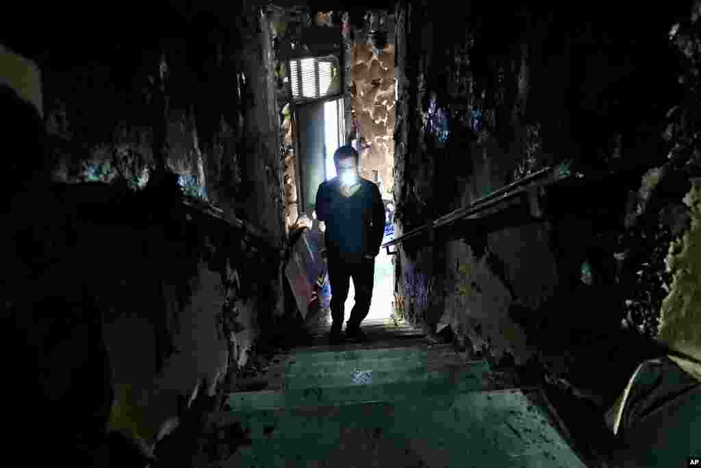 A man lights his mobile phone as he films the burned stairs of Tripoli municipality that was set on fire by protesters during a protest against deteriorating living conditions and strict coronavirus lockdown measures, in Lebanon.