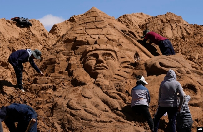 FILE - Artists work on a sand sculpture depicting a pharaoh and a pyramid, as part of Good Friday celebrations in Arenales de Cochiraya, on the outskirts of Oruro, Bolivia, Friday, April 7, 2023. (AP Photo/Juan Karita)