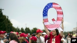 FILE - David Reinert holding a Q sign waits in line with others to enter a campaign rally with President Donald Trump in Wilkes-Barre, Pa. 