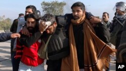 Pakistani police officers help their injured colleague during a clash with protesters in Islamabad, Pakistan, Nov. 25, 2017. Police launched an operation to clear an intersection where an Islamist group's supporters had camped out for the last 20 days, officials said Saturday. 