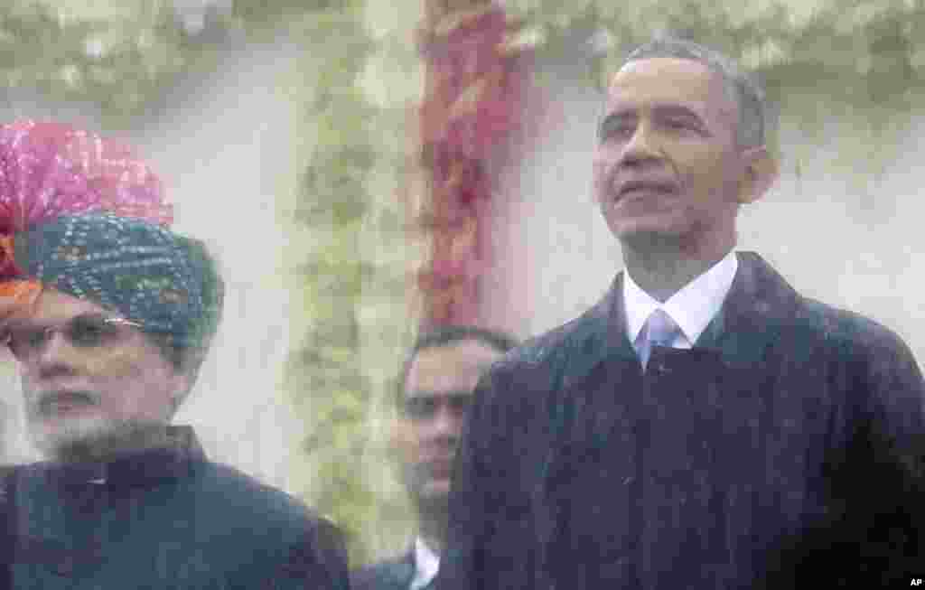 Indian Prime Minister Narendra Modi, left, and U.S. President Barack Obama, right, look out behind a rain covered protective glass to watch the Republic Day Parade in New Delhi, India, Jan. 26, 2015.