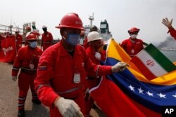 A Venezuelan oil worker holds a small Iranian flag during a ceremony marking the arrival of Iranian oil tanker Fortune at the El Palito refinery near Puerto Cabello, Venezuela, May 25, 2020.