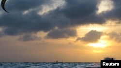 FILE - A kite surfer is seen silhouetted at the sunset while surfing a wave on his board during a kite surfing competition in Aruba, June 7, 2008. 