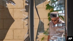 FILE - A Chinese Embassy employee examines broken windows after a bombing in Bishkek, Kyrgyzstan, Aug. 30, 2016. The blast was attributed to the East Turkistan Islamic Movement, a group once on the U.S. terrorism list but recently removed from it.