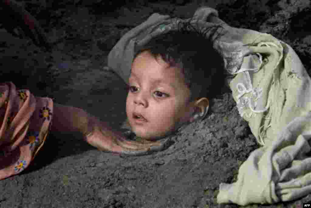 A Pakistani mother buries her child in mud during the solar eclipse in Karachi, Pakistan on Tuesday, Jan. 4, 2011. Superstitious people hope that burying ailing person during solar eclipse will cure them. (AP Photo/Fareed Khan)