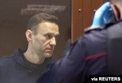Kremlin critic Alexey Navalny stands inside a defendant dock before a court hearing in Moscow, Feb. 5, 2021.