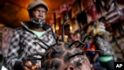 Gettrueth Ambio, 12, has her hair styled in the shape of the new coronavirus, at the Mama Brayo Beauty Salon in the Kibera slum, or informal settlement, of Nairobi, Kenya, Sunday, May 3, 2020.