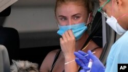 Seorang perempuan menjalani swab di klinik tes COVID-19 drive-through di Bondi Beach di Sydney, 21 Desember 2021. (Foto: AP)