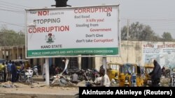 Un homme circule en moto près d'un panneau de campagne contre la corruption le long d'une route dans le district de Dangi dans la ville de Kano au nord du Nigeria, le 19 janvier 2016.