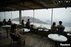 Couples enjoy the view while practicing social distancing during the global spread of the coronavirus disease (COVID-19), at an observatory near "N Seoul Tower" located atop Mt. Namsan in Seoul, South Korea, April 7, 2020.