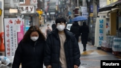 FILE - A couple wearing masks walks on a street during the COVID-19 pandemic in Seoul, South Korea, Dec. 13, 2020. The country saw a record number of marriages last year, possibly because weddings were delayed due to social restrictions during the pandemic. 