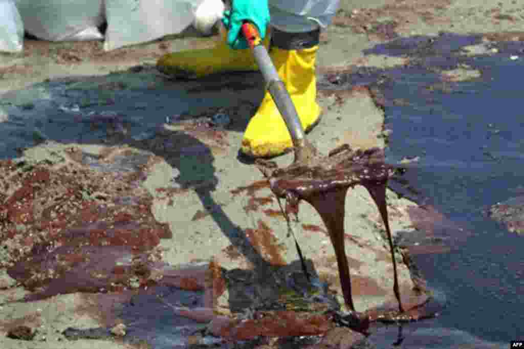 A BP cleanup crew shovels oil from a beach at Port Fourchon, Louisiana, 24 May 2010. (AFP Image)