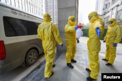 31일 중국 우한의 한 병원에서 방역복을 입은 장의사 직원들이 코로나바이러스 사망자 시신을 옮긴 후 서로의 몸에 소독액을 뿌리고 있다.