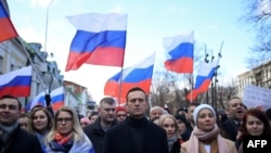 FILE - Russian opposition leader Alexei Navalny, his wife Yulia, opposition politician Lyubov Sobol and other demonstrators march in memory of murdered Kremlin critic Boris Nemtsov in downtown Moscow, Feb. 29, 2020. 