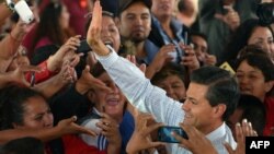 A handout photo released by the Mexican presidency press office shows President Enrique Pena Nieto (R) waving to supporters during the inauguration of the Women's Health City in Cuatitlan Izcalli, Mexico state on Nov. 18, 2014.
