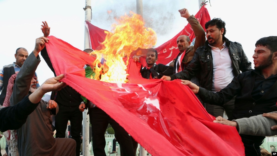 Iroqning Basra shahrida namoyishchilar Turkiya bayroqlarini yoqmoqda, Anqaradan qo'shinlarini chiqarishni talab qilmoqda, 18-dekabr, 2015-yil