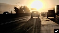 In this August 31, 2018, photo, morning commuters drive into downtown Los Angeles as the sun rises along Interstate 5.