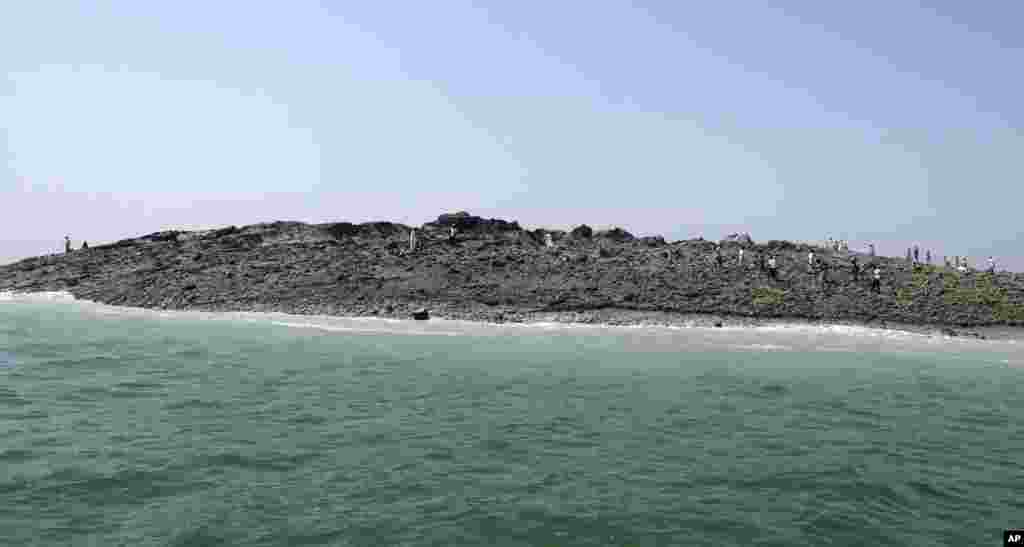 Dalam foto yang dirilis oleh kantor pemerintahan Gwadar, orang-orang berjalan di atas pulau kecil yang dilaporkan muncul di pesisir Gwadar, Laut Arab, akibat gempa besar di Pakistan.