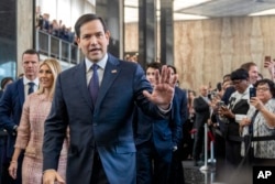 Secretary of State Marco Rubio greets people as he arrives to speak to State Department staff followed by his family, at the State Department in Washington, Jan. 21, 2025.