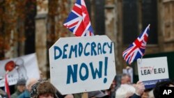 FILE - Pro-Brexit demonstrators wave flags and banners outside Parliament in London, Nov. 23, 2016.