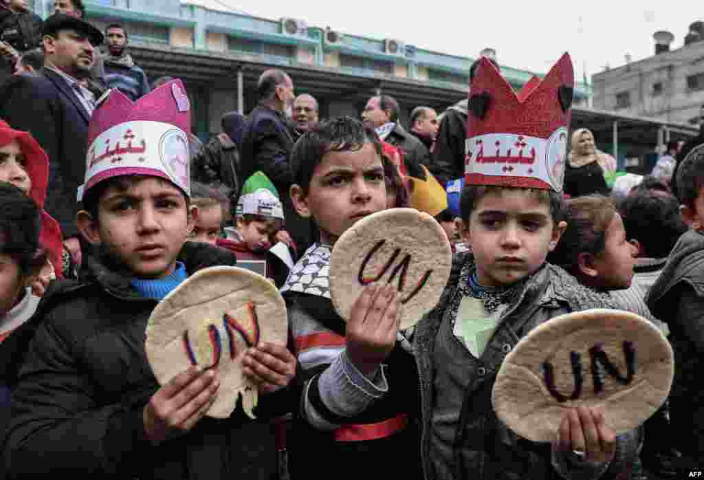 Palestinian children hold bread patties during a protest against aid cuts, outside the United Nations&#39; offices in Khan Yunis in the southern Gaza Strip.