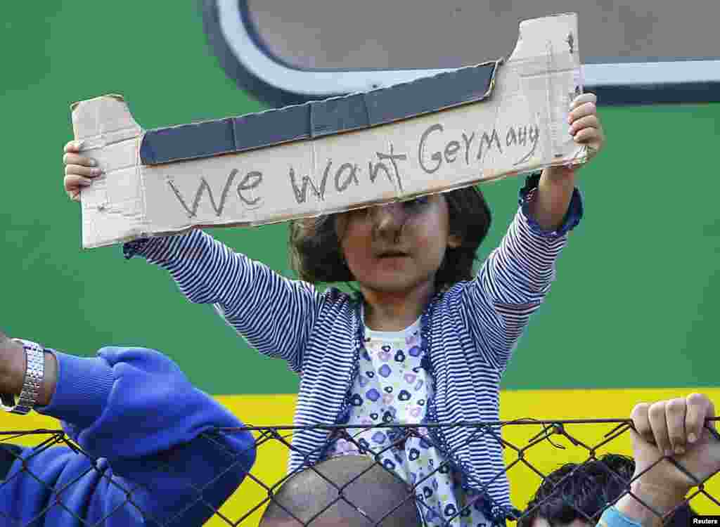 A young migrant girl holds up a sign during a protest in front of a train at Bicske railway station, Hungary, Sept. 4, 2015. 