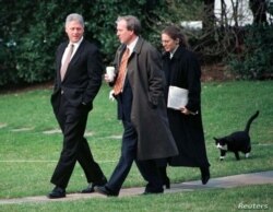 Socks (Calcetines), llamado así por sus patas blancas, camina detrás del presidente Bill Clinton, a la izquierda, en el césped de la Casa Blanca, el 6 de marzo de 1997.