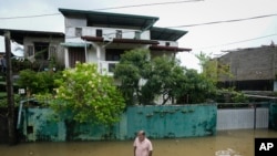 A man wades through his flooded neighborhood in Colombo, Sri Lanka, Monday, Oct. 14, 2024. 