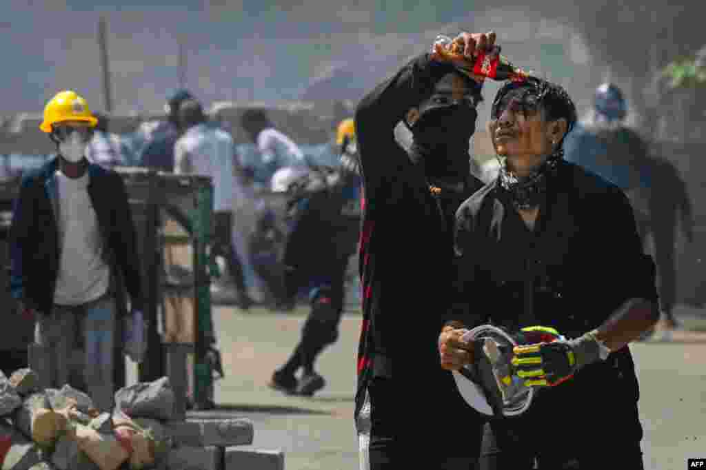 A protester pours soda on the face of a comrade to diminish the effects of tear gas during a crackdown by security forces in Yangon&#39;s Thaketa township.